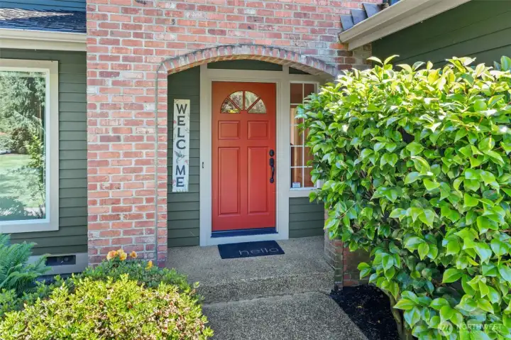 The entry features a charming red door framed by classic brick detailing and an arched surround, both keeping your guests dry while creating instant warmth and character.