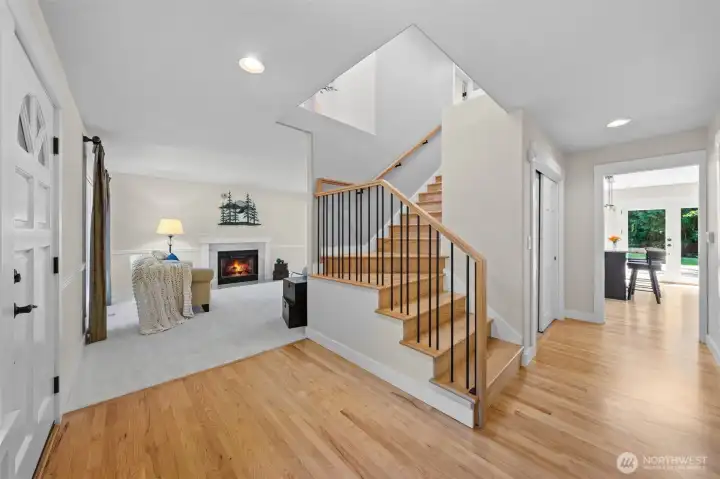 Welcoming entry introduces the home’s fresh interior finishes, hardwood floors, updated trim, custom staircase railing, and easy flow toward the formal living spaces and kitchen beyond.