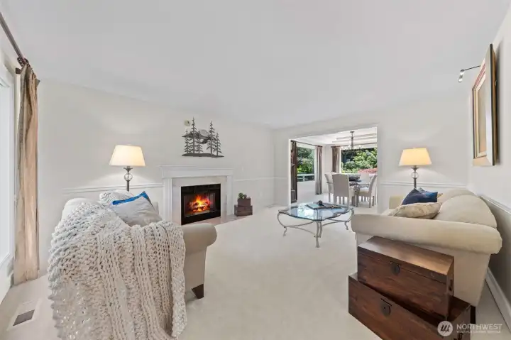 The formal living room feels warm and refined with a classic fireplace, elegant chair railing, soft neutral tones, and a graceful connection to the dining room.