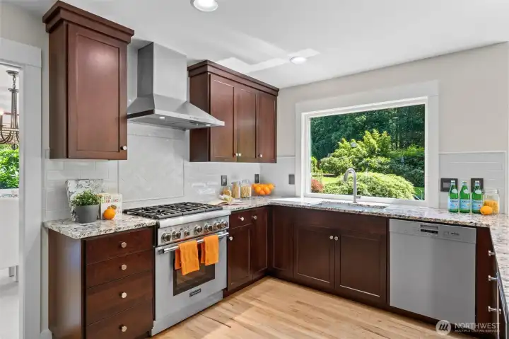 Designed for both everyday cooking and entertaining, the updated kitchen features cherry wood cabinetry, granite counters, a Thermador range, exterior-vented hood, and a gorgeous view over the backyard gardens.