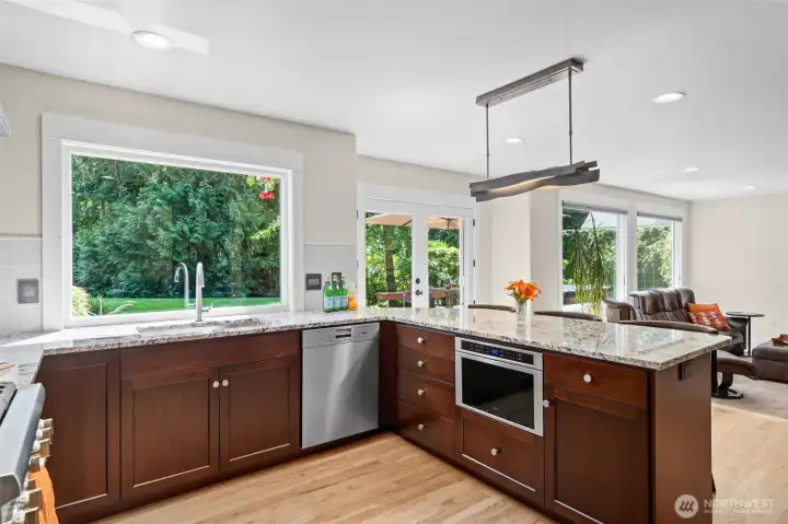 A beautifully updated kitchen pairs rich cherry cabinetry with granite countertops, recessed lighting, and a generous peninsula workspace that opens easily to the adjoining living area.