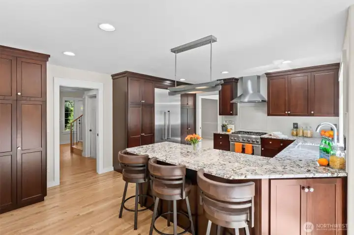 You'll love the sense of space in this chef's kitchen, where the cabinets wrap around the kitchen for easy entertaining. A vented stainless range hood, gas range, and built-in refrigerator make this a true cook's dream, while the open flow to the hallway and staircase keeps the home connected. Bright windows and recessed lighting fill the space with everyday warmth and natural light.