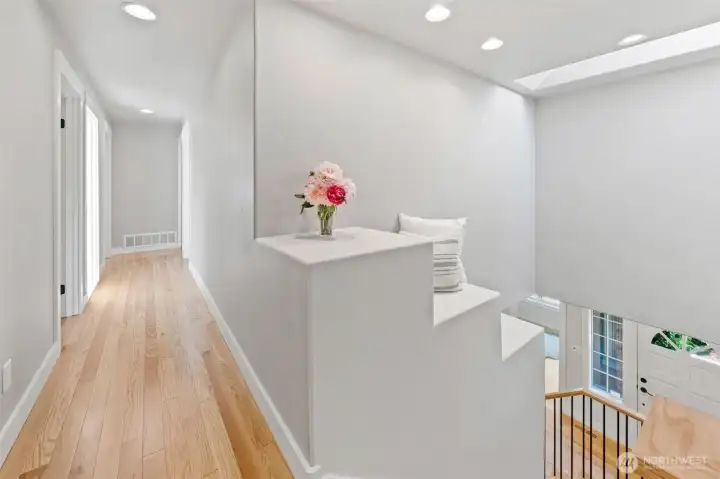 The main hallway features hardwood floors, a skylight, and a built-in architectural interest that overlooks the staircase below, with all bedrooms nestled together for an easy, connected layout. Don't miss the abundance of natural light flowing throughout, creating a bright and welcoming path to every room.