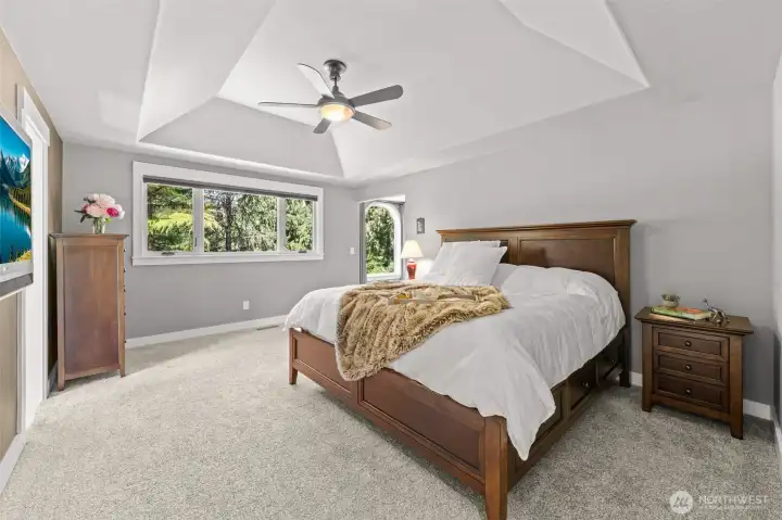 Welcome to the Primary Suite features soaring tray ceilings, a designer fan, and a wall of windows overlooking a canopy of mature trees — with an elegant arched window framing the private sitting area beyond. The Primary Bedroom shares no walls with any other bedrooms, providing true peace and quiet. This suite is the ultimate sanctuary, complete with spa-inspired ensuite bath and walk-in closets designed for two.