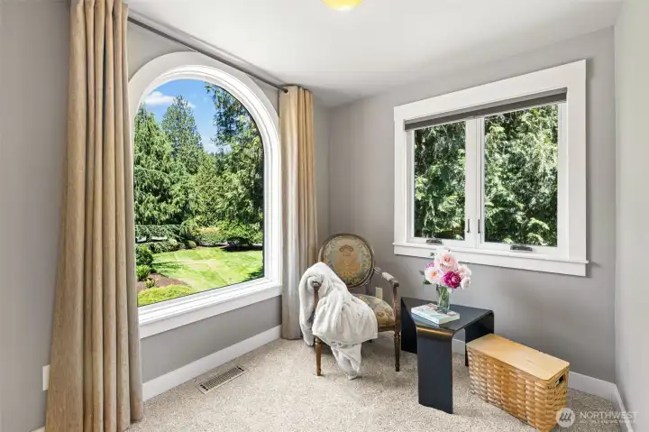The Primary Suite features a sitting room, with charming arched window that frames the peaceful garden views. Perfect for morning coffee or quiet reading. Two casement windows and plush carpet add warmth and versatility to this private retreat.