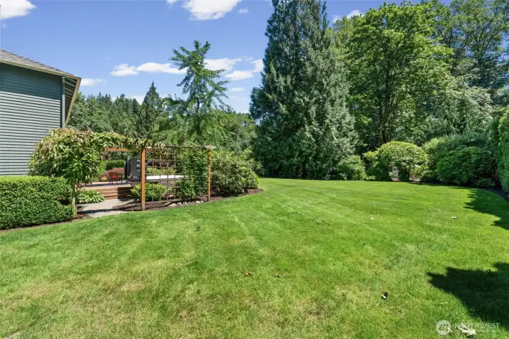 The backyard features a cedar pergola by the hot tub that's framed by a vibrant perennials and connected to the lawn by a paver path. Don't miss the layered greenery and rhododendrons surrounding the space, creating a private retreat just steps from the back door.