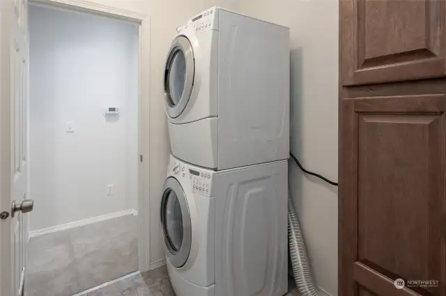Stack washer/dryer and cabinets in laundry room.