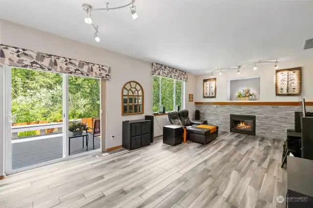 Family room with custom lighting, sliding glass door out to the newer composite Deck, and that wonderful backyard! Look at that remodeled and updated gas fireplace with Stone tile surround!  Oak mantle that goes all the way across...amazing!