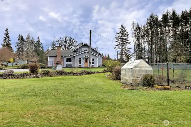 Green house and fenced garden area. It even has netting over the top of it to protect the berries.
