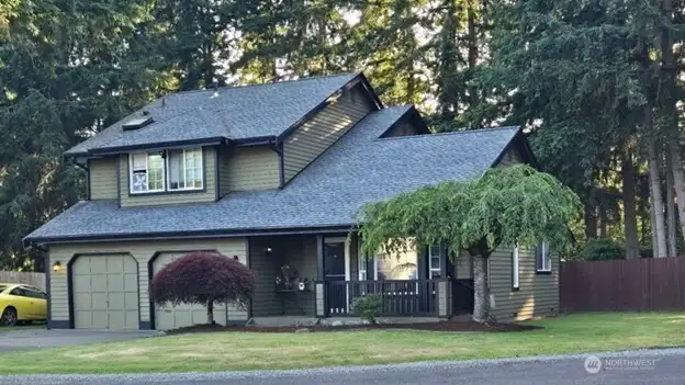 Welcome home to 25608 68th Ave E—this striking front exterior shot showcases the home’s curb appeal with a lush green lawn, long driveway, and charming covered porch. Surrounded by serene trees and natural privacy, this property blends country comfort with Northwest style. Ideal for buyers seeking peace, space, and practicality.