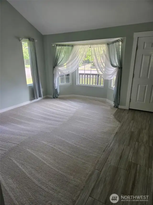 Natural light pours into this formal living room through a large bay window with charming sheer drapes. Plush carpet and luxury tile flooring create a welcoming and stylish first impression.