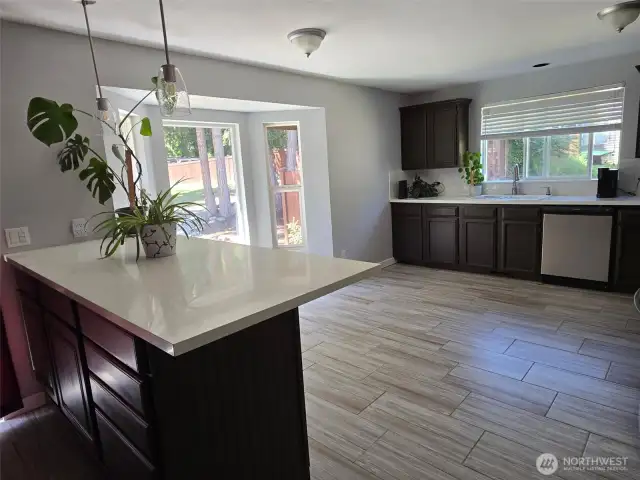 Sun-filled kitchen nook framed by bay windows offers a beautiful space for casual meals, with backyard views and ample natural light.