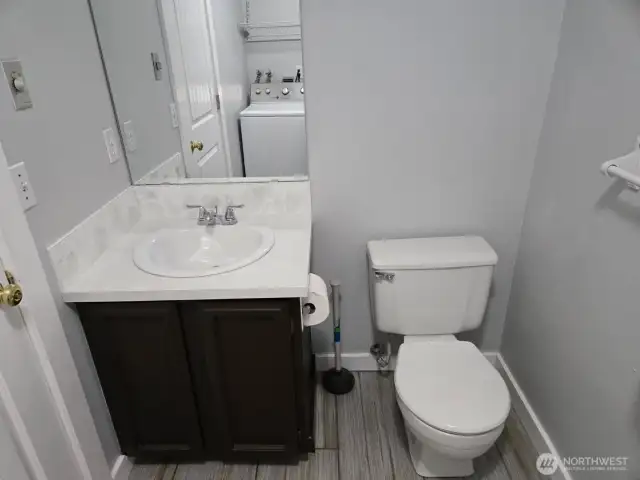 Main-level half bath with shared laundry room. Features updated flooring and stylish vanity for a modern touch.