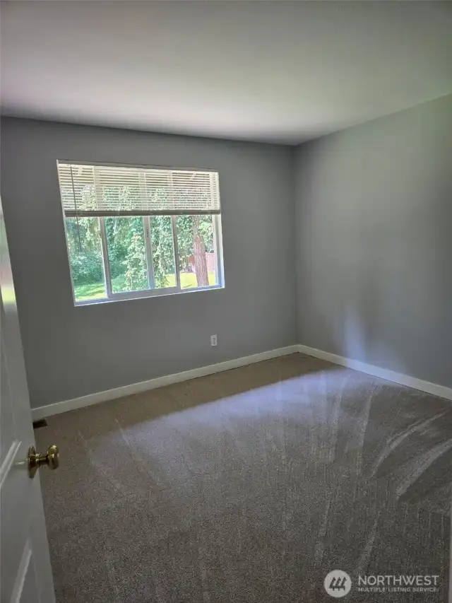 Enjoy a peaceful view of the tree-lined backyard from this bright and airy bedroom. Soft natural light and newly updated carpet make this a cozy and restful retreat.