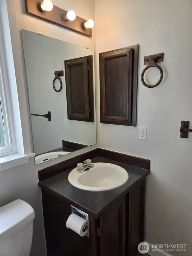 This modern guest bathroom features a sleek countertop, classic vanity, and full wall mirror.