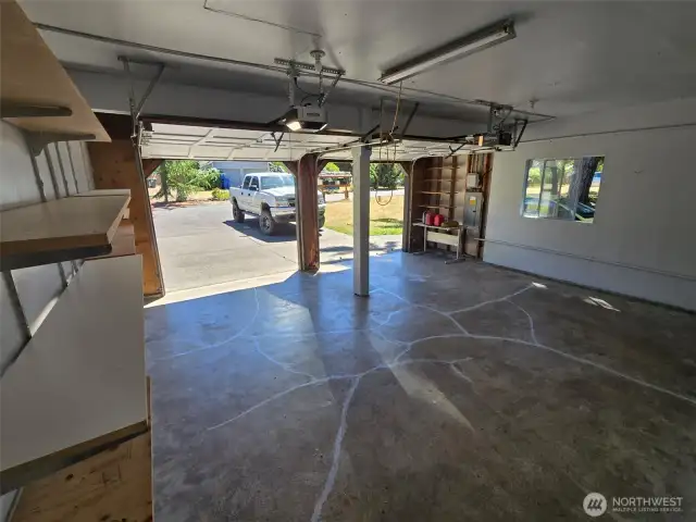 Spacious two-car garage with automatic openers and overhead lighting offers plenty of room for vehicles, tools, and hobbies. A built-in workbench and wall shelving provide ideal organization for any DIY enthusiast.