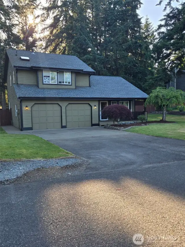 Double garage and spacious driveway offer ample parking at this beautifully maintained home with inviting curb appeal, mature trees, and vibrant lawn in a serene neighborhood setting.
