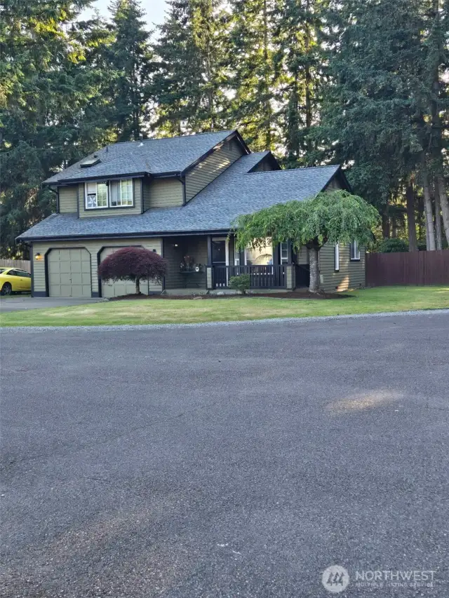 Charming two-story, architectural roof, and manicured landscaping. The front porch offers a welcoming entry with space for seating, framed by mature trees for privacy.