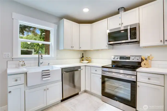 A perfect blend of style and function—this beautifully remodeled kitchen showcases a sleek new farm sink and a full suite of modern appliances, including a dishwasher, microwave, and range/oven. The elegant tile backsplash adds a polished finishing touch to this thoughtfully designed space.