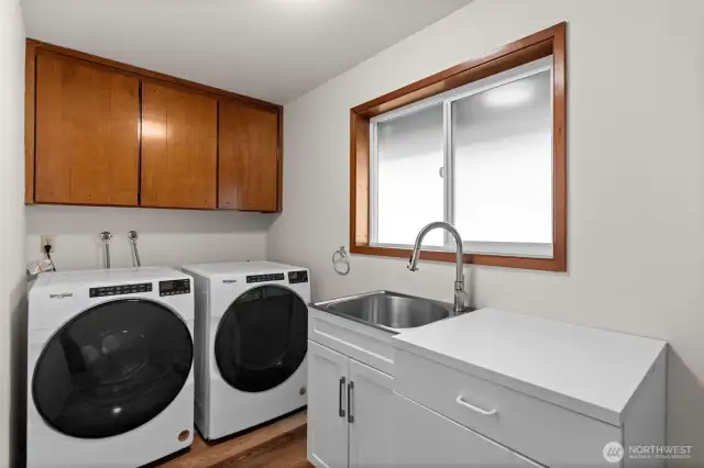 Spacious laundry room with ample cabinetry and a convenient utility sink.