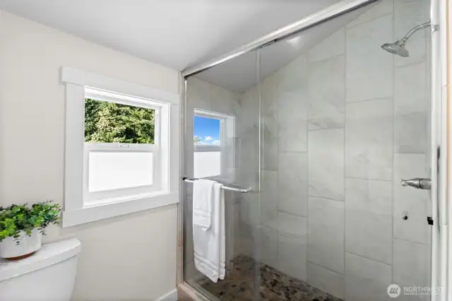 The primary bathroom is spacious and luxurious, featuring quartz countertops and tile floors.