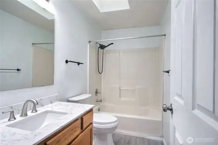 Full bath upstairs displaying new countertop, skylight and flooring