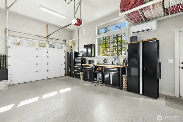 A large garage with high ceilings and garage doors, lots of natural light and epoxy floors.