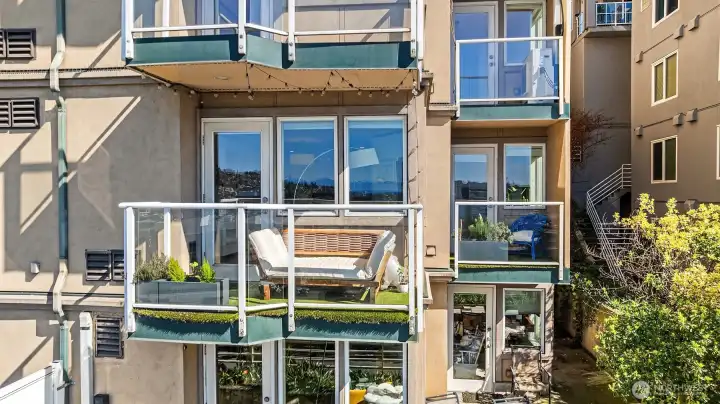 West-facing balconies off of living room and primary suite are both featured in this photograph.