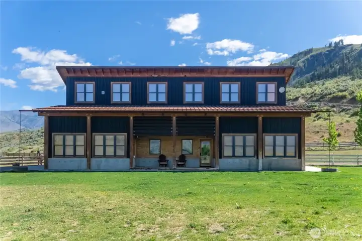 The two story barn has a wall of windows and a covered porch.