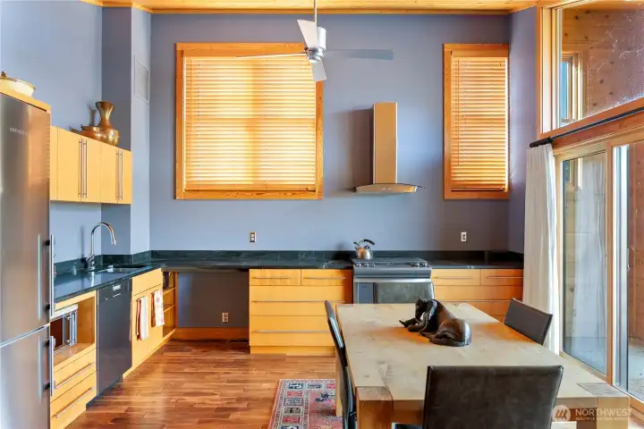 The kitchen has high ceilings and is brightly lit with natural light.