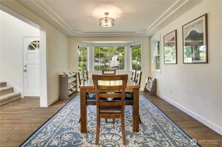 A bright two-story entry introduces the home's hardwood floors, new in 2024 as part of the kitchen remodel and main-level improvements. The adjacent dining room features a bay window, cove ceiling details, and updated baseboards. A bright two-story entry introduces the home's hardwood floors, new in 2024 as part of the kitchen remodel and main-level improvements. The adjacent dining room features a bay window, cove ceiling details, and updated baseboards.