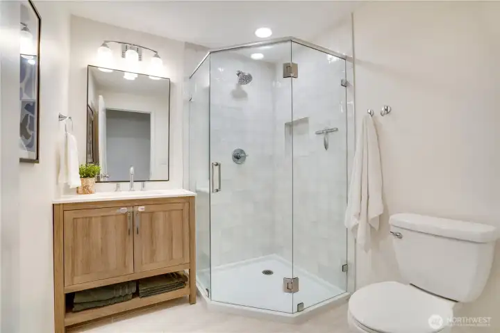 Recently added, this main-floor ¾ bath includes a glass-enclosed shower, quartz vanity, durable tile flooring, and updated lighting. Recently added, this main-floor ¾ bath includes a glass-enclosed shower, quartz vanity, durable tile flooring, and updated lighting.