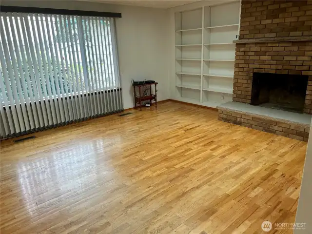 Living Room With The Original Hardwood Floors, Built-In Shelving, Brick Fireplace, Large Window Letting The Natural Light Shine In & Skylights Too!