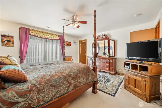Primary suite with door to private bathroom and ceiling fan.