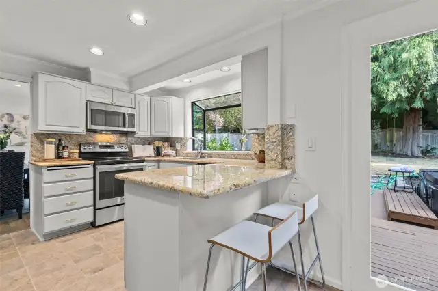 Kitchen with granite counters, stainless appliances, and a garden window showing off the backyard.
