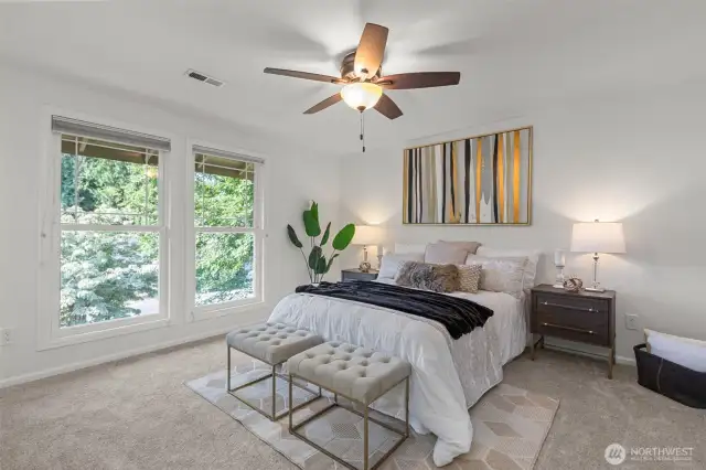 The primary bedroom with Southerly facing windows and ceiling fan lights