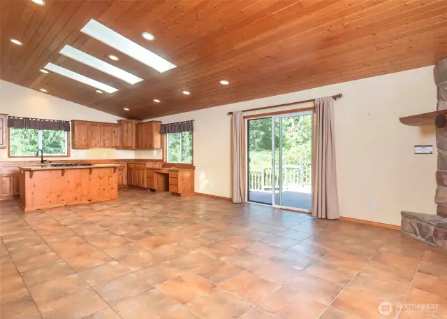 This open-concept great room boasts soaring ceilings, a crackling wood-burning fireplace, skylights, tongue-and-groove finishes, and a sliding door that opens to your private backyard.
