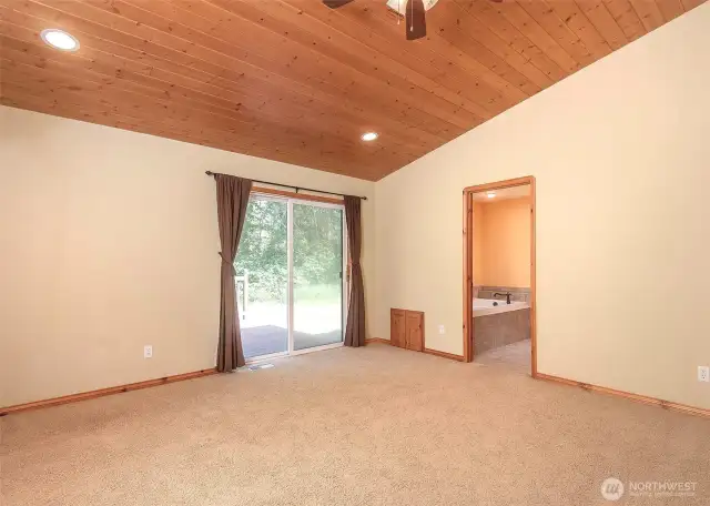 The primary suite showcases beautiful tongue-and-groove ceilings and offers direct access to the backyard deck