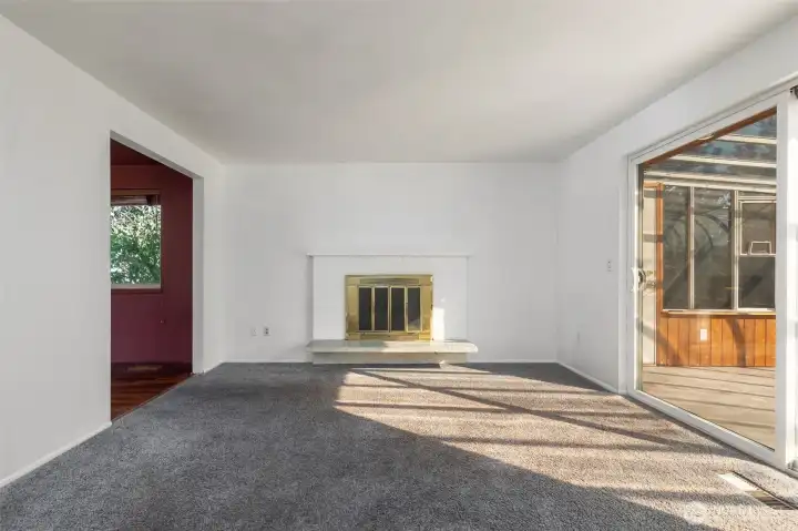 Living room with fireplace, opens to sun room to right and dining room to left.