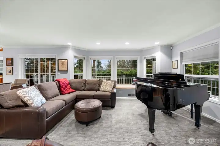 A large wall of window with a window seat look out to the sunset and the wrap around deck.