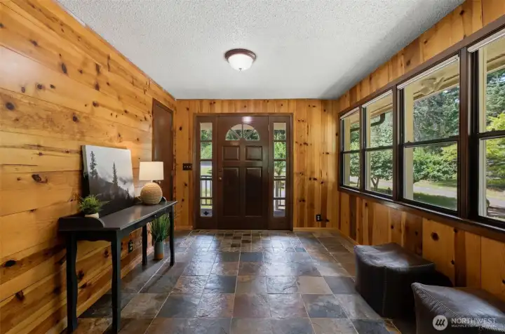 A warm welcome: The entry features beautiful, rich wood walls and beautiful slate tile flooring. The door and window casings were just recently stained.