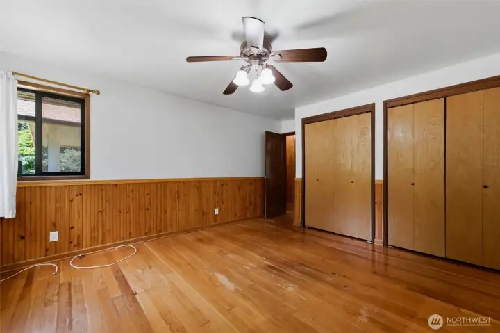 This generous second bedroom is perfect for guests, featuring rich wood-toned flooring and great natural light.