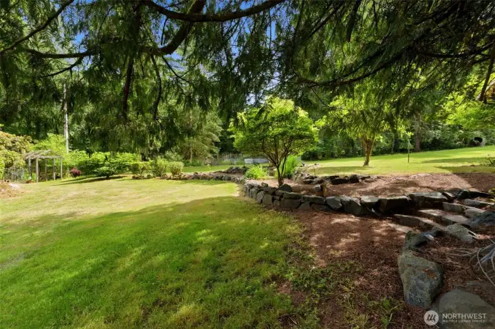 Charming stone steps add a touch of natural landscaping, connecting the open lawn to your private garden oasis.