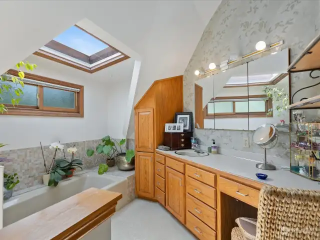 Primary Bathroom with large counter & skylight over the bathtub.