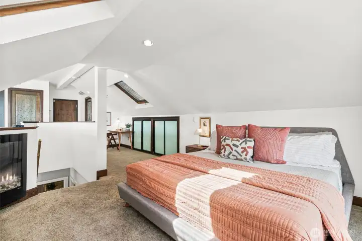 The primary bedroom features vaulted a fireplace, an en suite bath, a walk in closet, built-ins, and skylights. It's a unique and beautiful space.