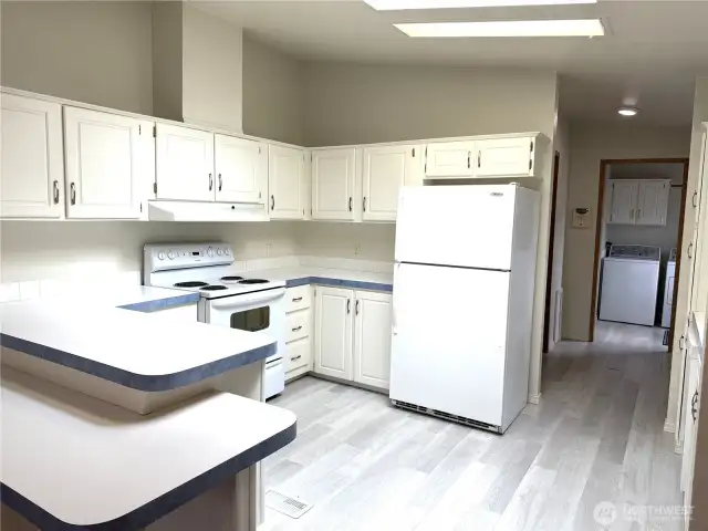 Nice sized kitchen with all the appliances. Leads to the mud room in the background. New flooring throughout.