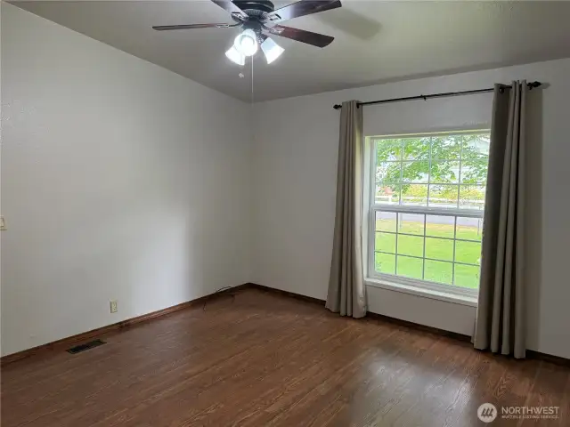 Primary bedroom with ceiling fan and large windows.