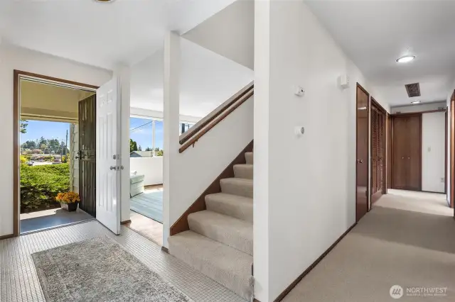 View towards the entry, and wide stairs heading to the primary suite and additional upstairs bedroom