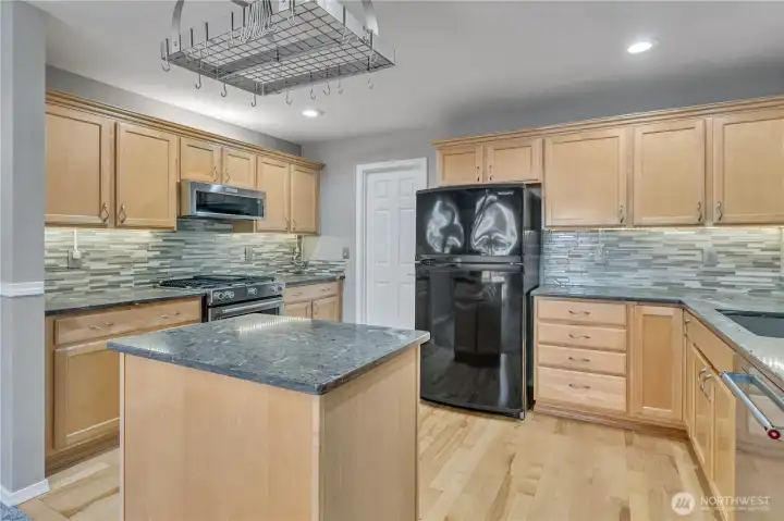 Chef’s kitchen with abundant cabinetry and quartzite counters. Full-height backsplash adds a stylish modern touch.