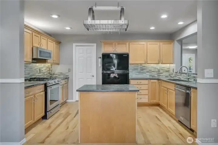 Thoughtful kitchen layout with generous counter space. A pot rack offers both function and flair.